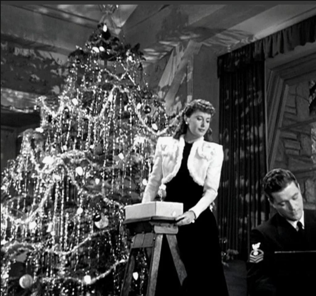 Image of Barbara Stanwyck next to a Christmas tree in "Christmas in Connecticut."